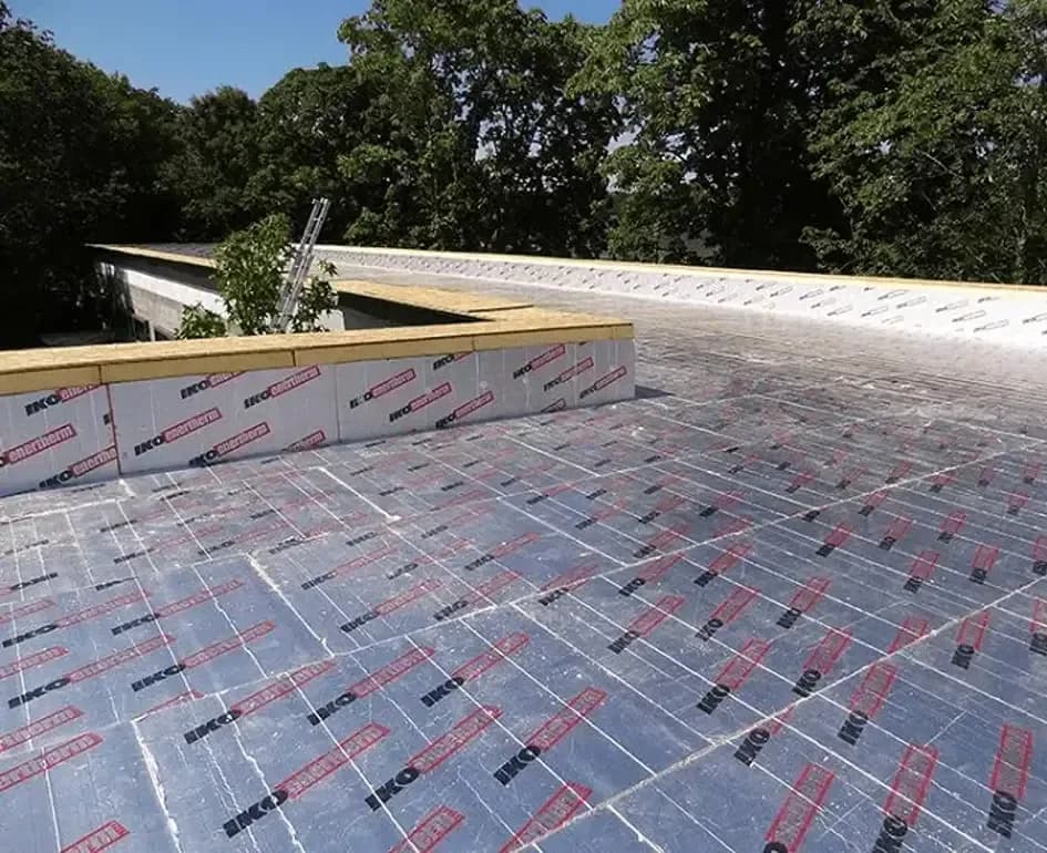 Vakman brengt PIR-isolatieplaten aan op plat dak voor renovatie