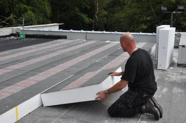 Vakman werkt aan dampremmer en isolatie op plat dak