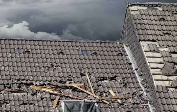 Stormschade aan een dak in Nederland met losgewaaide pannen